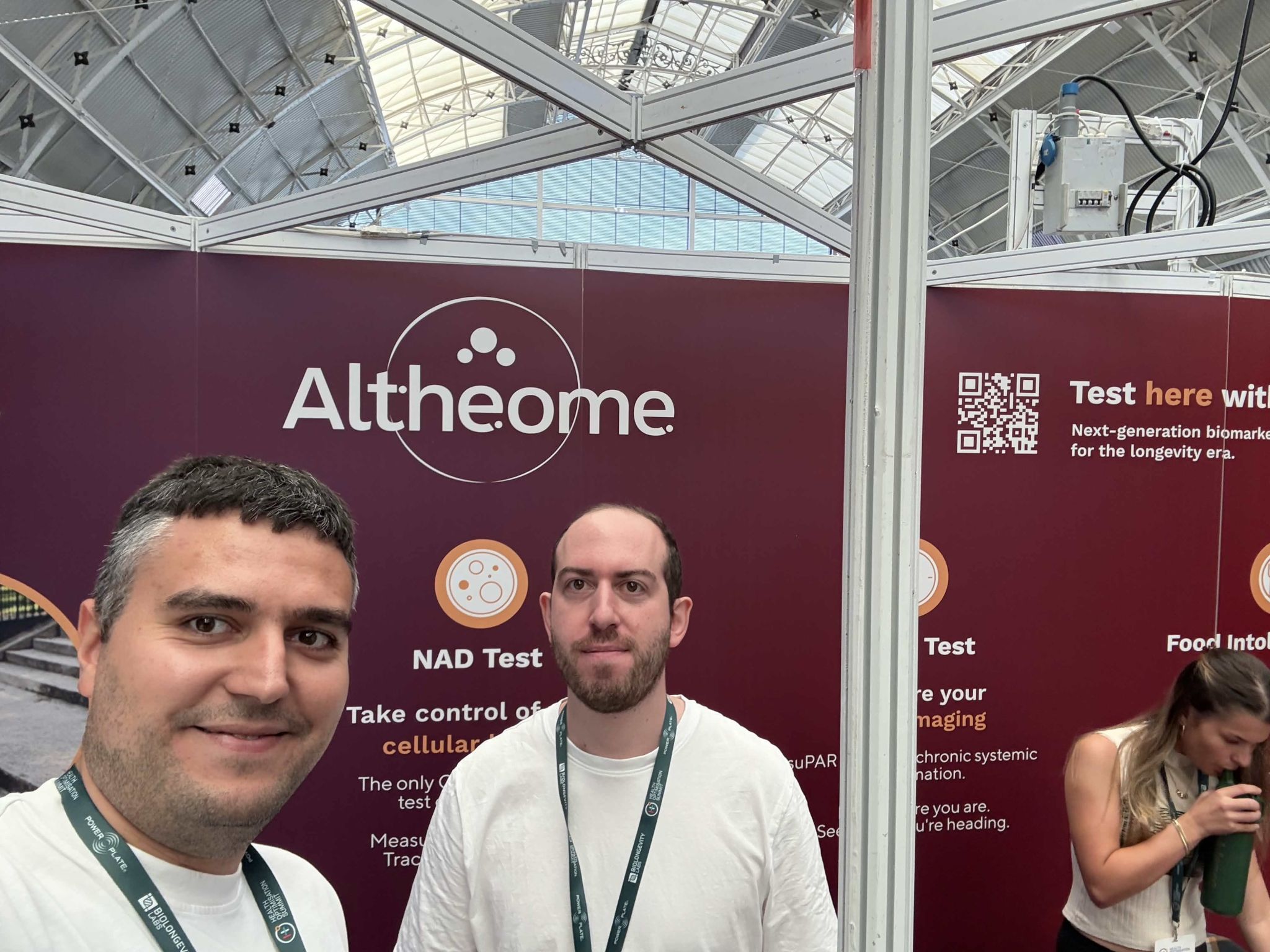 Two xHeal team members at the Altheome stand, whose banner reads 'Next-generation biomarker for the longevity era'