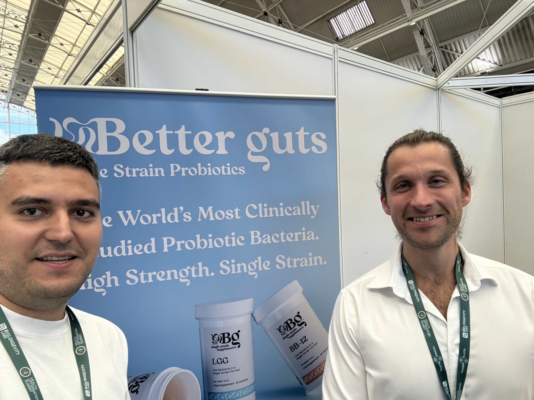 An xHeal team member and a visitor in front of the Better Guts stand, showing single-strain probiotic products