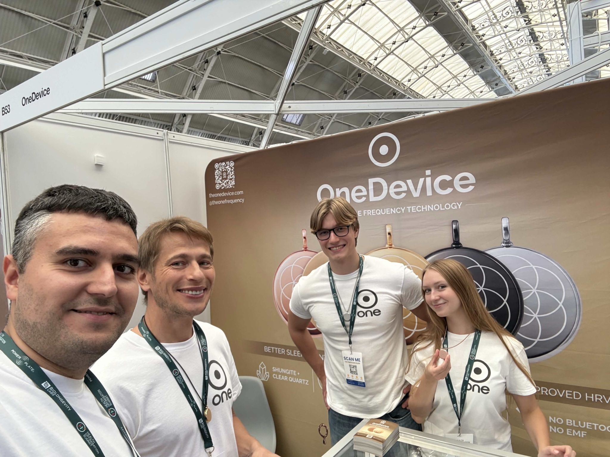 An xHeal team member and three OneDevice staff beside their wearable frequency technology stand